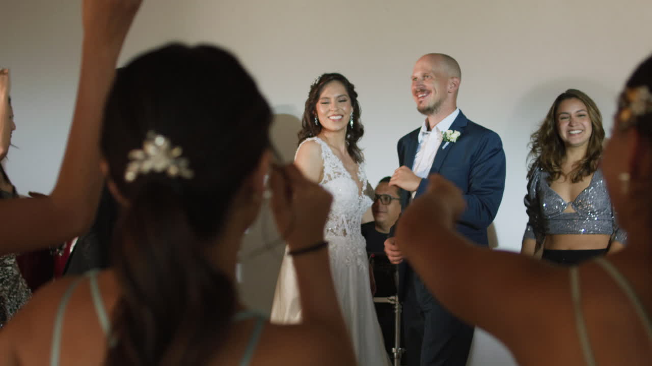 Clip of a wedding where the newlyweds dance happily with their guests and bridesmaids.