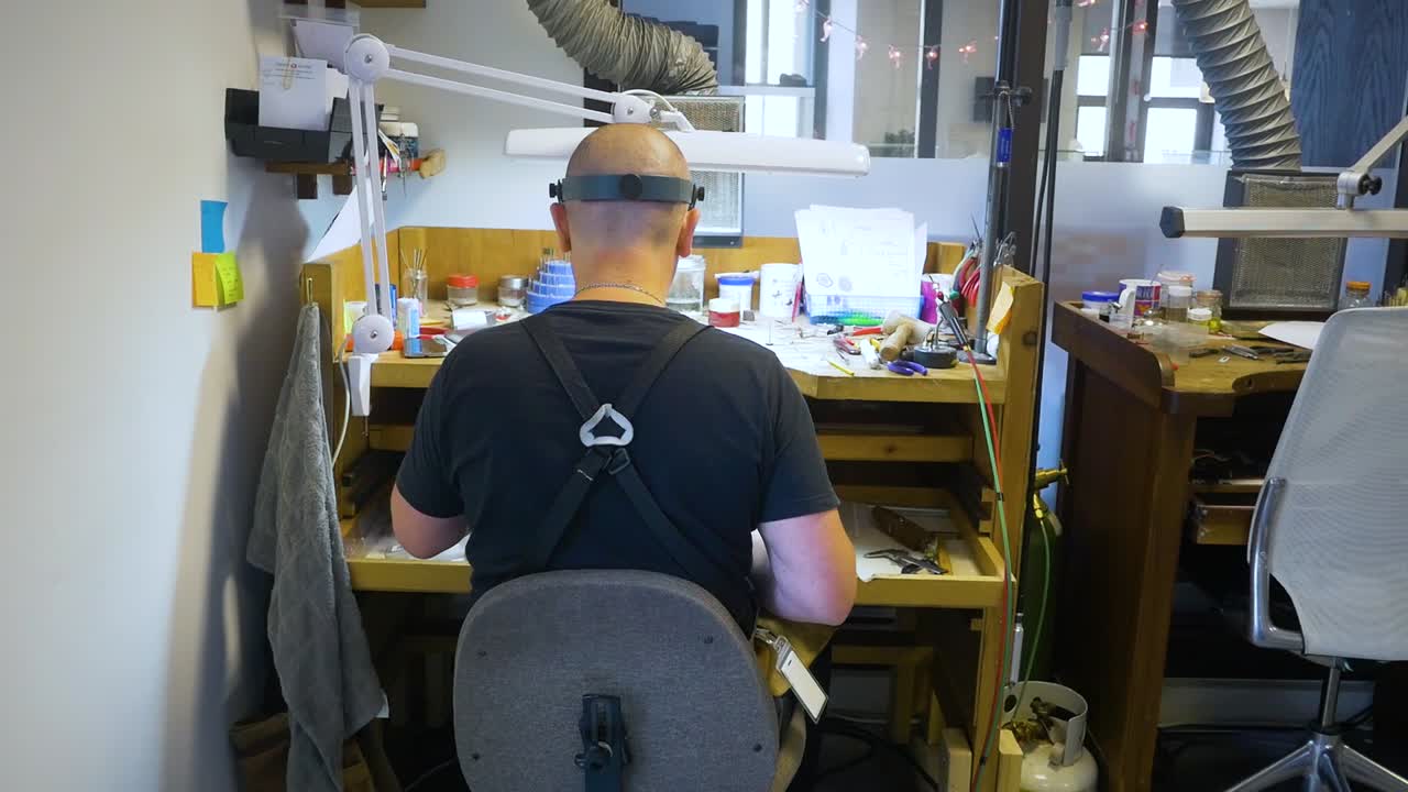 남성 보석 제작자가 보석 제작 워크숍에서 은반지를 연마하고 연마합니다.