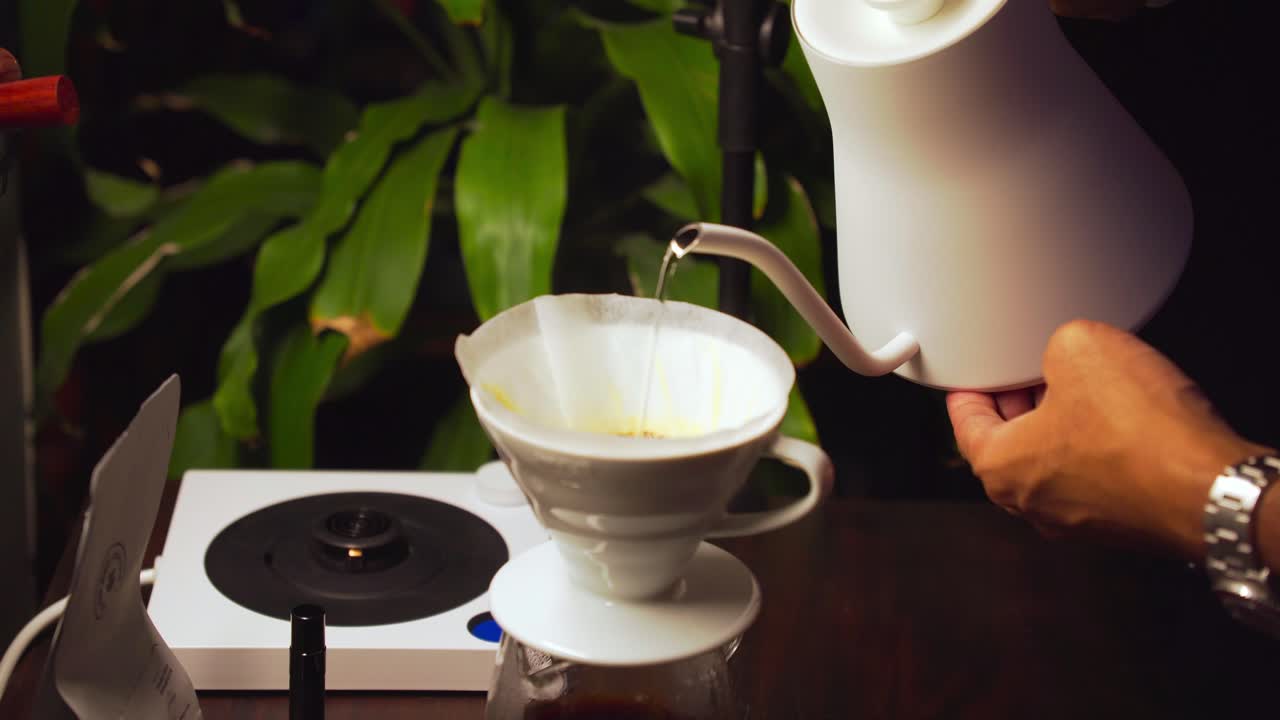 바리스타는 필터가 있는 세라 드립러에 은 커피 위에 뜨거운 물을 부어줍니다.