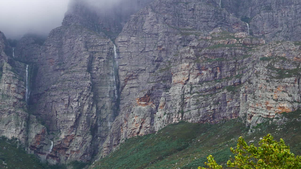 múltiples cascadas cayendo por la ladera de la montaña después de fuertes lluvias, toma panorámica ampliada