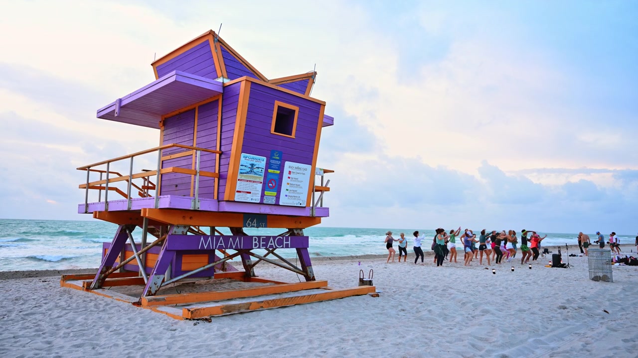 Miami, EE. UU., 16 de abril de 2026: Torre de salvavidas morada y naranja en la arenosa playa de Miami Beach. Puesto de salvavidas de madera pintado de morado y naranja en una playa de arena con olas del océano bajo un cielo nublado.