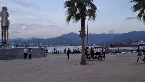 batumi ali and nino statue in windy day with tourists and palm trees.