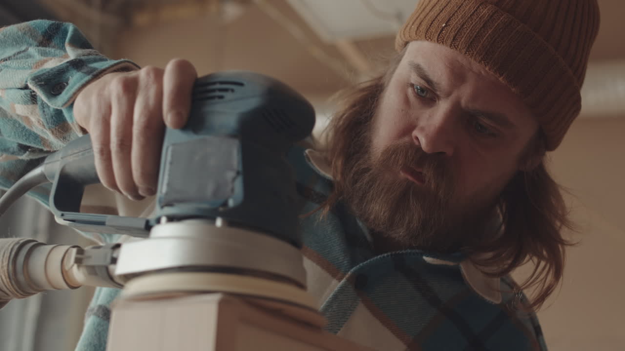 Bearded Craftsman Sanding Wooden Box in Workshop