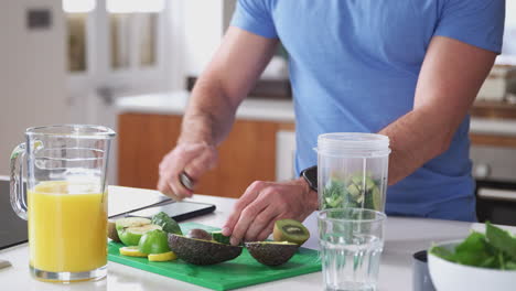 primer plano de un hombre haciendo una bebida de jugo saludable con ingredientes frescos en un exprimidor eléctrico después del ejercicio