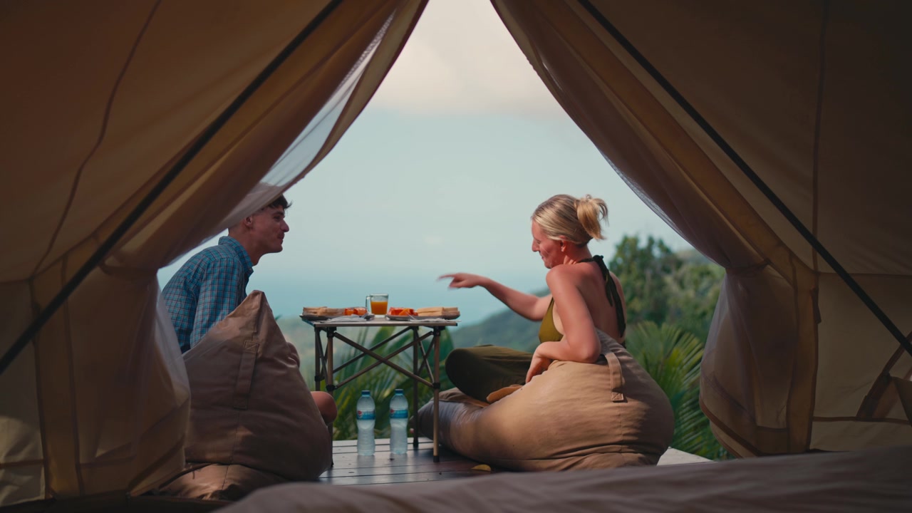 Coppia che fa colazione fuori dalla tenda glamping nella natura