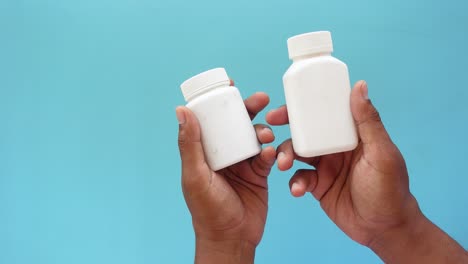 primer plano de manos sosteniendo dos frascos de pastillas vacías