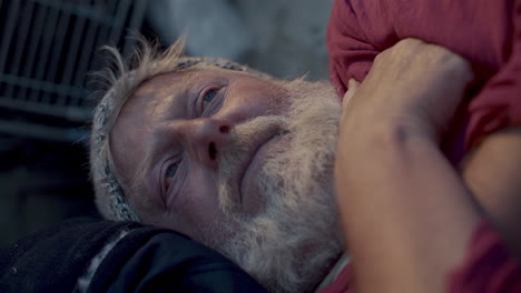Elderly Homeless Man Lying on Sidewalk, Looking away Pensively