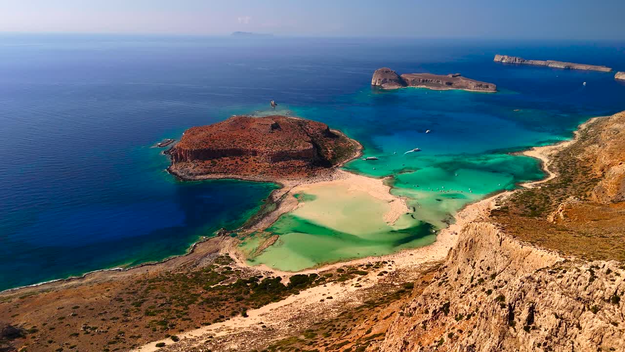 Observe the breathtaking views of untouched coastlines and turquoise waters surrounding a secluded island. The scenery showcases sandy beaches and rocky formations under a clear sky