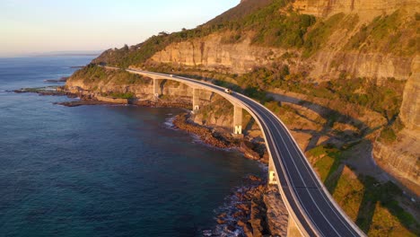 sea cliff bridge during golden hour of sunrise with mountain cliffs in nsw, australia