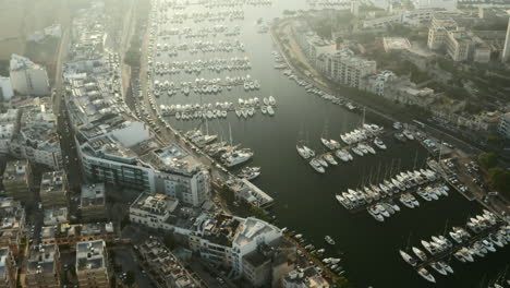 Sailboat-Port-with-white-Yachts-and-Boats-in-Sunlight-Morning-on-Marina-Malta,-Aerial-tilt-down