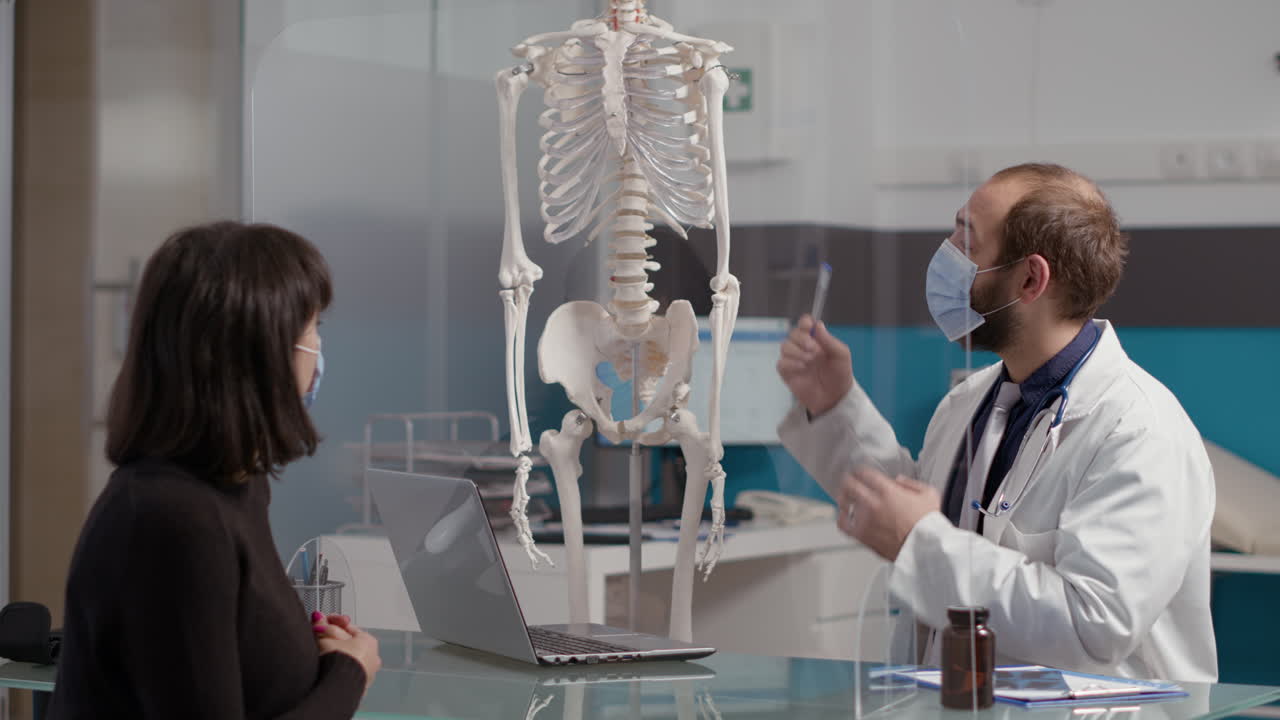 Health specialist pointing at human skeleton to explain osteopathy