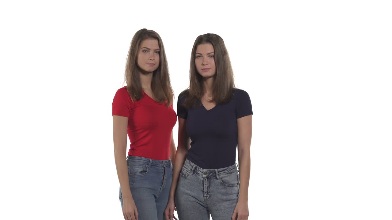 Young Caucasian twin sisters showing o-key sign. Approving hand gesture. Isolated on white background