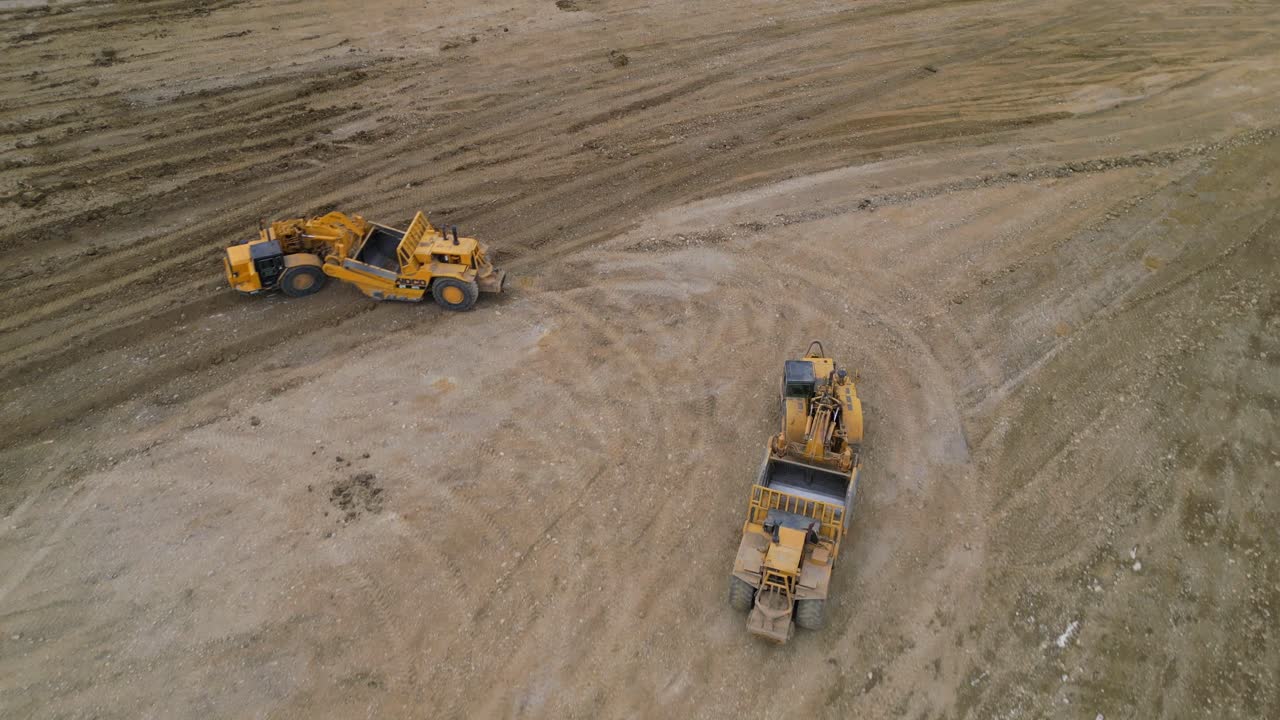 двухколесные тракторные скреперы разравнивают землю на месте будущего строительства жилья