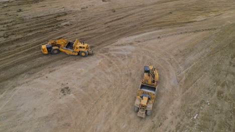 two wheel tractor scrappers are levelling the ground of a future site for housing