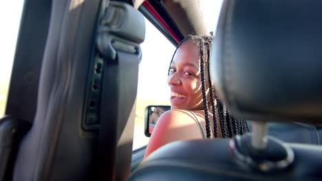 young african american woman smiles from the driver's seat on a road trip, with copy space