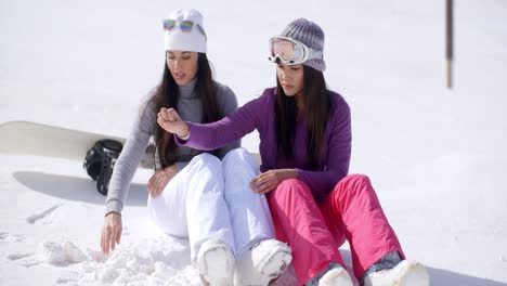 two young women sitting waiting in the snow