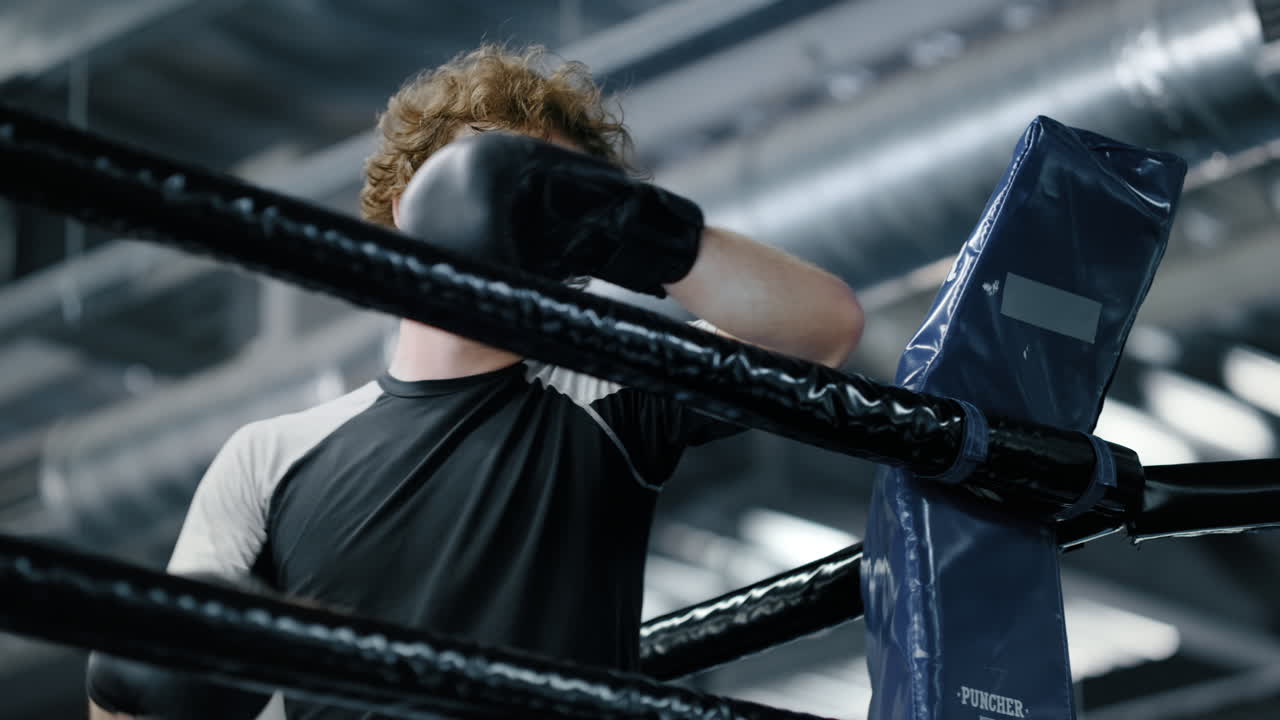 удрученный боец стоит в фитнес-центре. кикбоксер опирается на веревки в тренажерном зале.