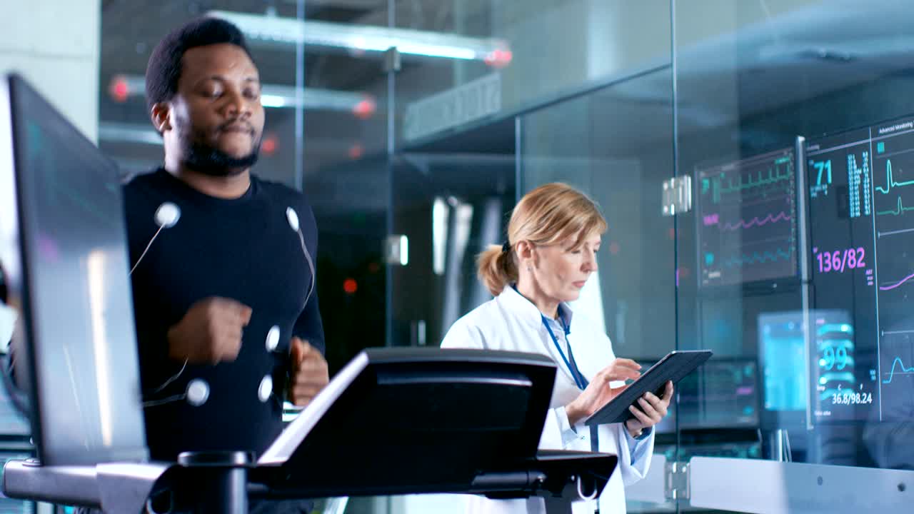 Atleta maschio corre su un tapis roulant con elettrodi collegati al corpo, mentre uno scienziato dello sport tiene un tablet e supervisiona lo stato dell'ECG. Sullo sfondo, un laboratorio con attrezzature ad alta tecnologia.