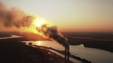 dirty smoke from industrial chimneys at sunset. dark chemical fumes released into the atmosphere in the evening. harmful emissions in the environment. aerial view.