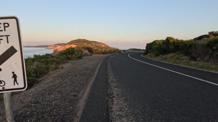 Strada con segnale di tenere la sinistra vicino alla costa