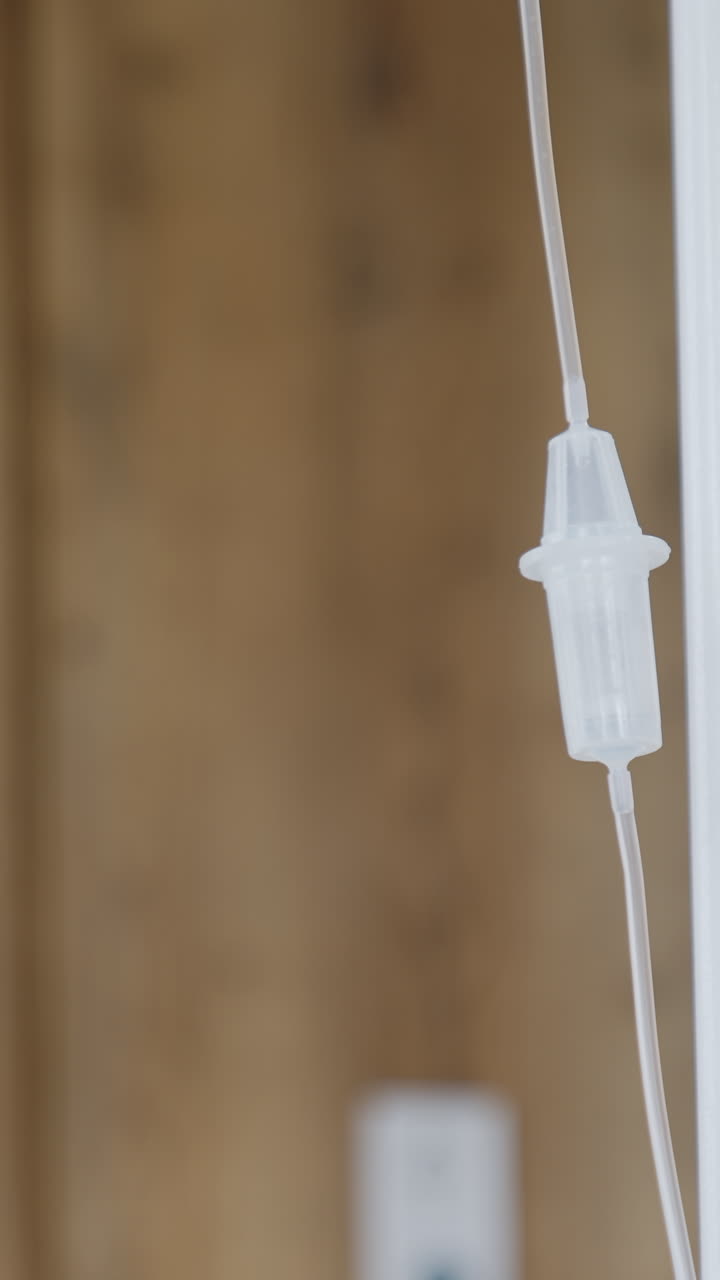 Flebo di plastica appesa e che ondeggia. Attrezzatura in sala parto. Sfondo sfocato. Video verticale.