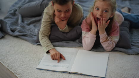 boy reading fairy tales to excited little girl. siblings enjoying reading home