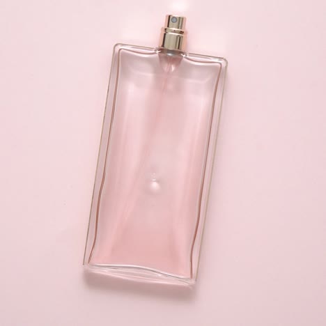 top view of luxury bottle of perfume on pastel pink surface  minimal composition  flat lay