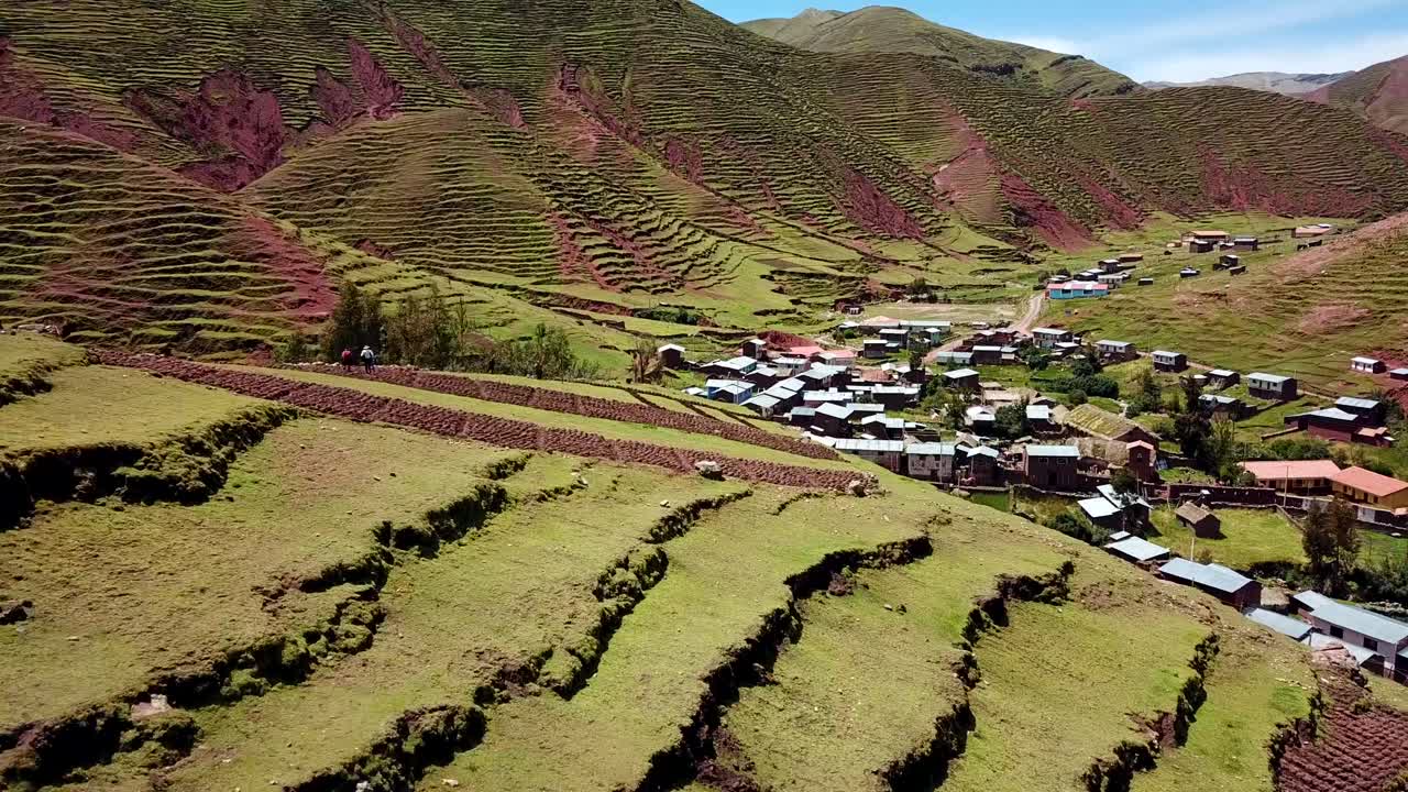 Ripresa aerea con drone sopra le terrazze Inca, che rivela una piccola città vicino alla montagna Palcoyo, in una giornata di sole, a Cusco, Perù, Sud America