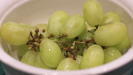 fresh green grapes, ready to be eaten, are seen in a white bowl