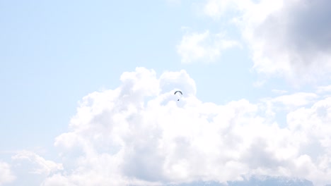 paratrooper in the sky on a colorful parachute flying between clouds, sunny day