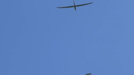 glider plane and motor plane flying in the sky on clear bright day