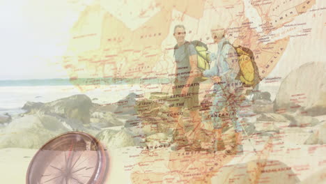 two hikers trekking rocky shoreline, showcasing africa map overlay and metal compass for education