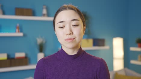 asian woman looking at camera with unhappy and tired eyes.