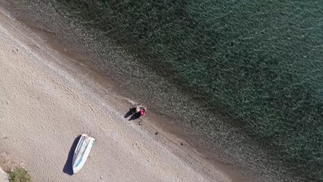 Aerial-bird's-eye-flight:-Married-couple-sitting-in-a-camping-chair-on-the-sea,-Turkey