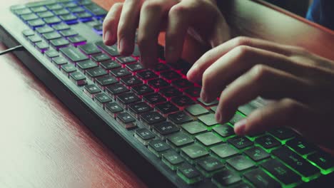 a man types text on a backlit keyboard 01