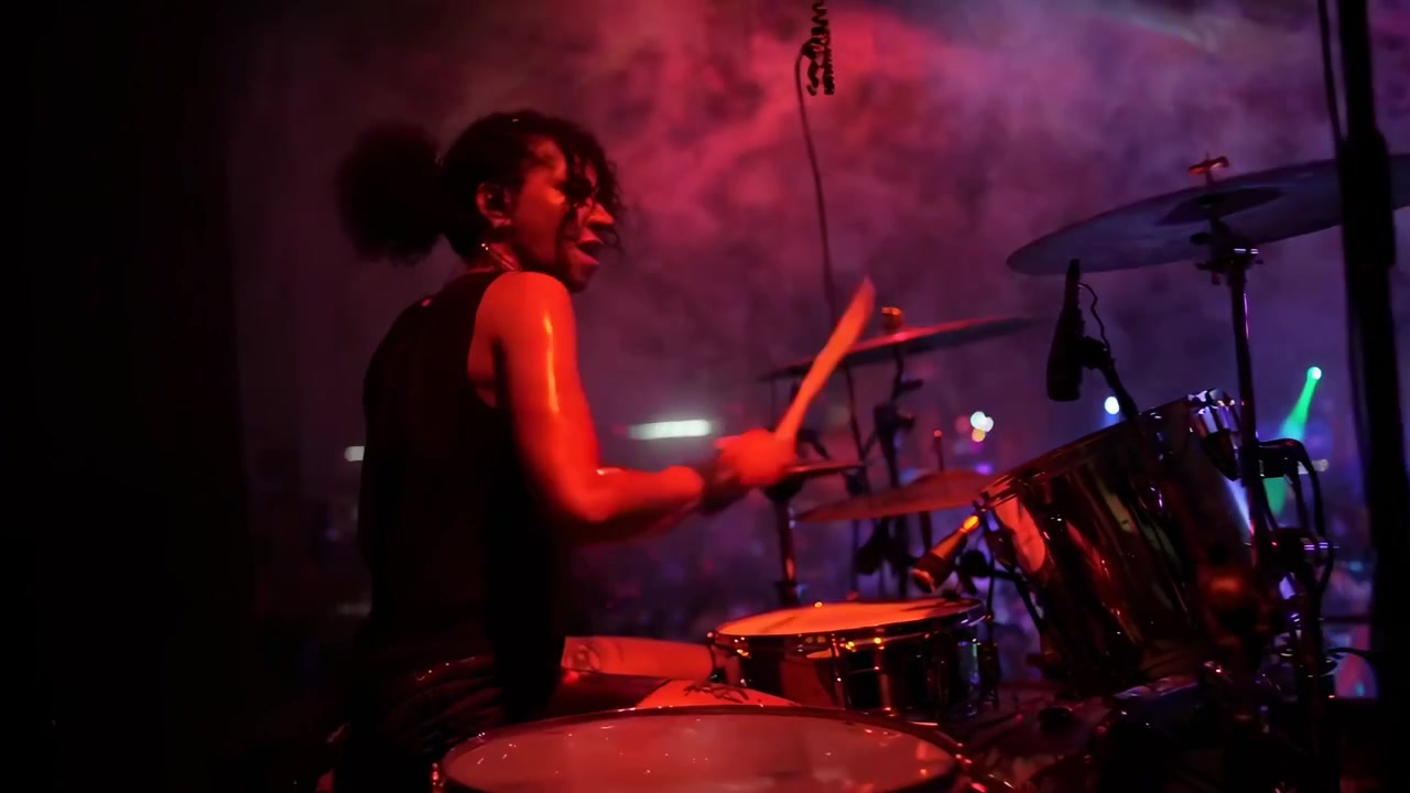 Batterista donna energica che si esibisce dal vivo sul palco a un concerto