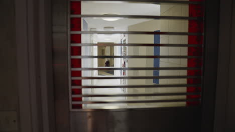 Peering through metal window grates into hallway of home apartment building, pull back through house