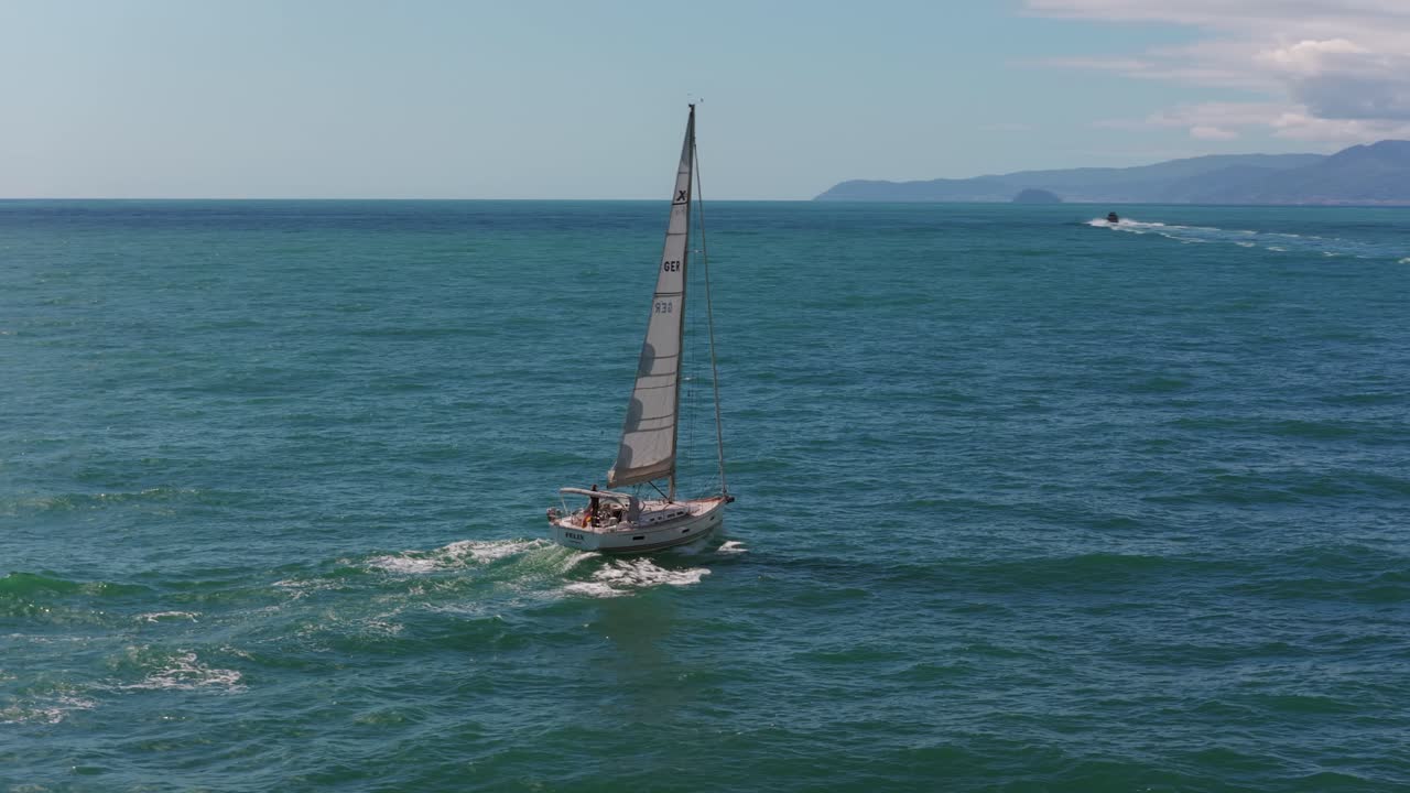Sailboat sailing on sea blue ocean water under cloudy sky. Ideal for travel, adventure, freedom, leisure, nature, and establishing shots