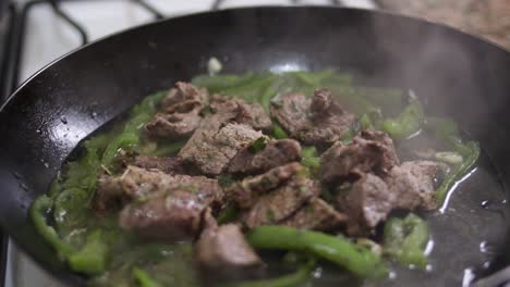 closeup uncovering smoking pan with meat and green pepper