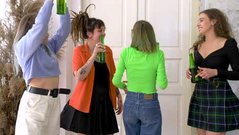 group of four happy girl friends holding beer and dancing during a party at home 3