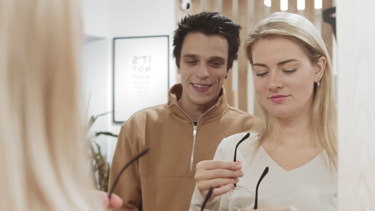 оптометрик помогает женщине выбирать очки в магазине