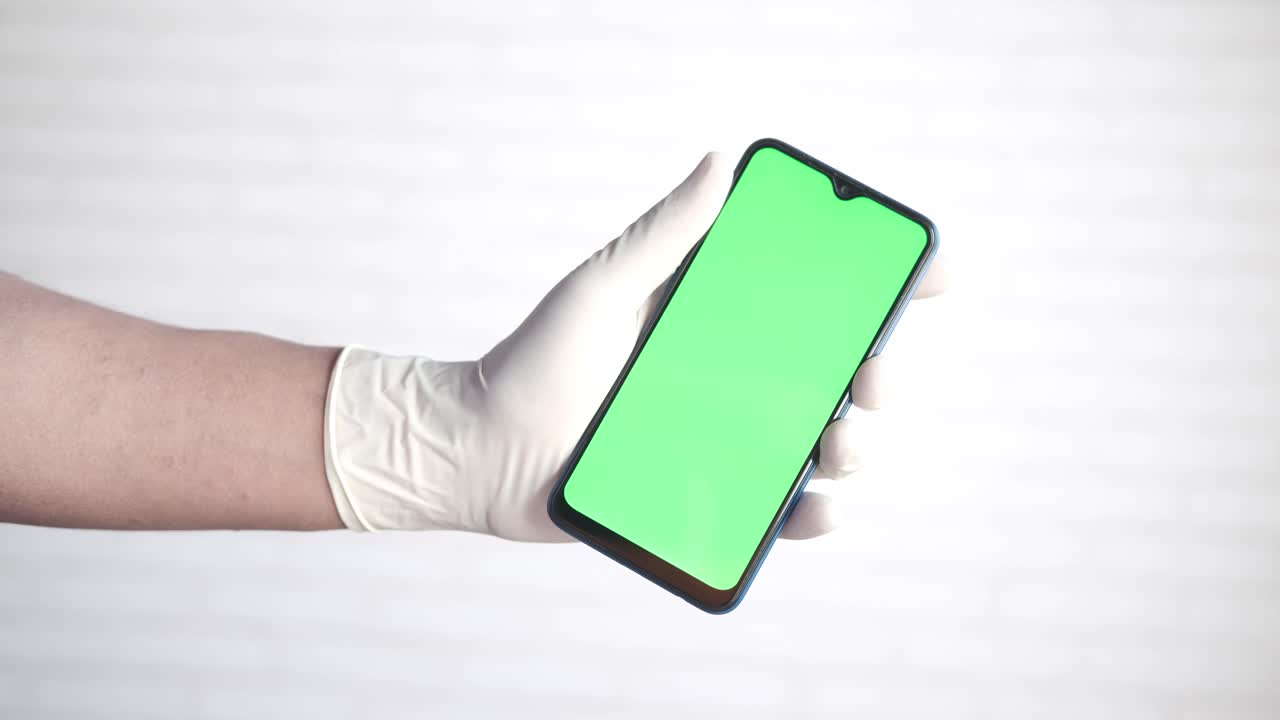 en el guante de la mano sosteniendo un teléfono inteligente con pantalla verde