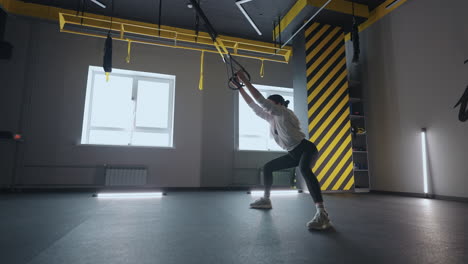 sporty woman doing trx exercises in the gym. women training with fitness straps in the gym. beautiful lady exercising her muscles sling or suspension straps.