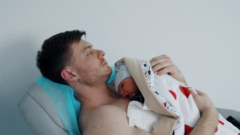 caucasian man holding a newborn son on his chest. skin to skin concept in maternity clinics.