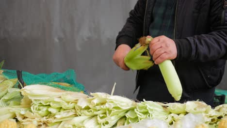 a man selling corn on the cob at a market stall.