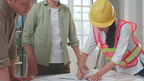 three asian engineers with helmets and a man celebrating finish drawing building construction while working at the office