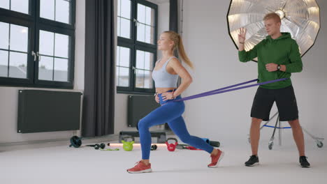 young fitness couple perform lunges using a resistance band