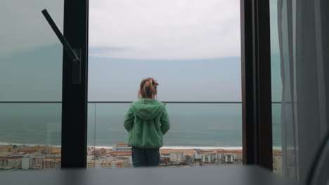 child looking at ocean coast from the hotel balcony