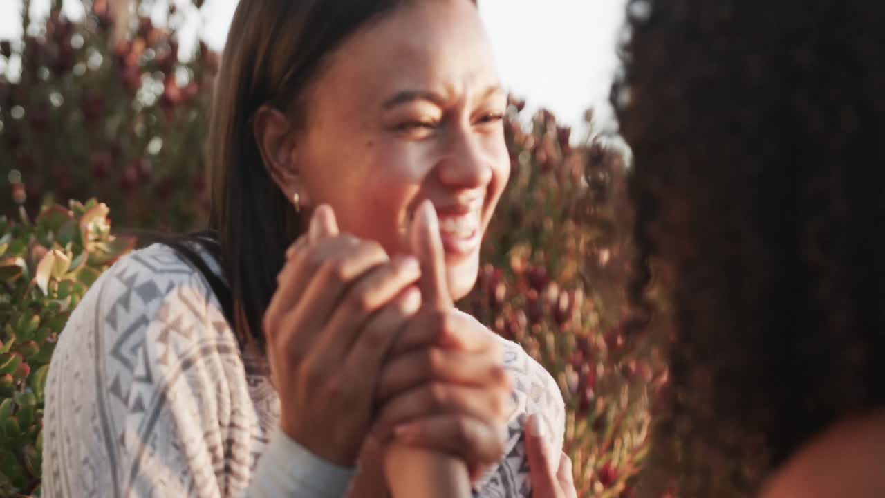행복한 로맨틱 한 종족 레즈비언 커플이 일몰 때 정원에서 얘기하고 포옹하고, 느린 동작