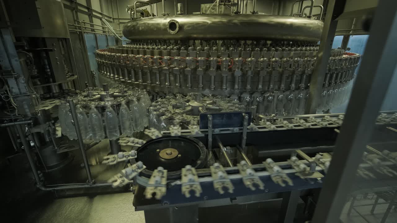 Automatic filling machine pours water into plastic PET bottles at modern beverage plant